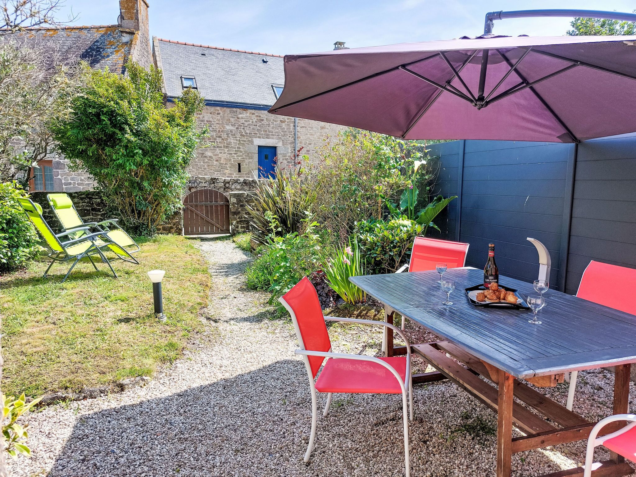 A patio with a table and chairs, a large umbrella, and a stone building in the background.