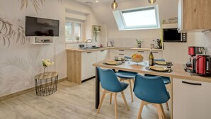 A modern kitchen with a central island, blue chairs, a TV, and a skylight. - Vacation home Hoedic by Interhome (Plouhinec Morbihan)