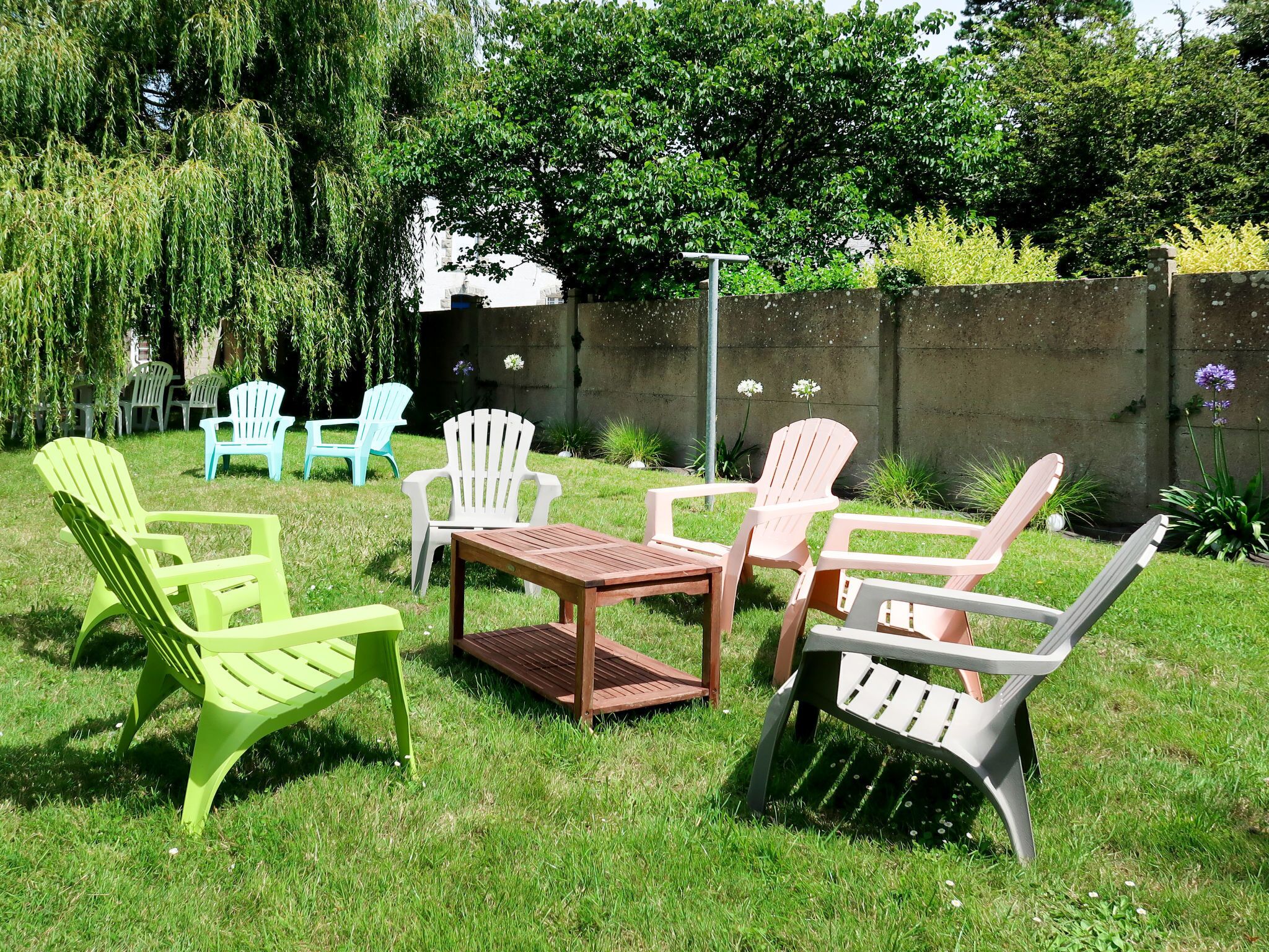 An outdoor seating area with multiple Adirondack chairs and a wooden table.