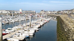 A marina with numerous boats docked along a stone quay, surrounded by buildings and a clear sky. - La Farniente by Interhome (La Turballe)
