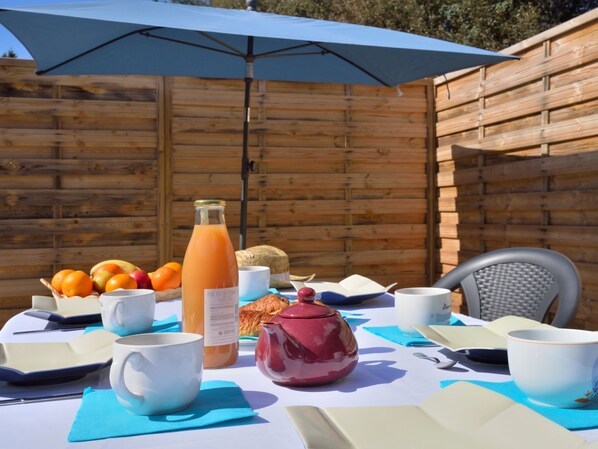 Enjoy a casual meal under the shade of a blue umbrella at this outdoor dining setup.