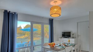 A modern room with a dining area, a TV, and a view of a garden.