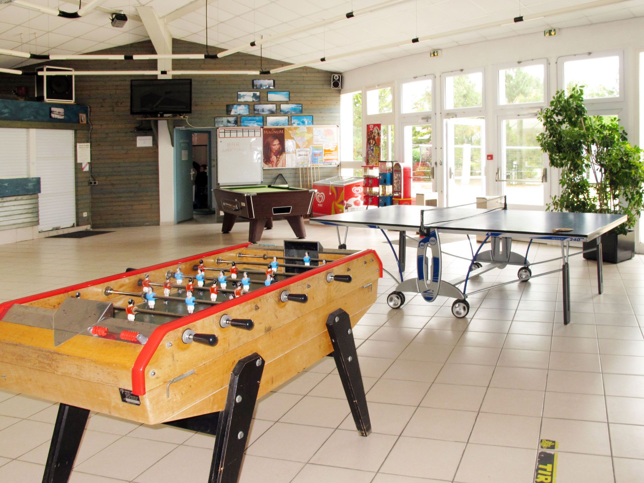 Een recreatiegebied met een tafelvoetbaltafel, een pingpongtafel en een pooltafel.