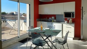 A modern kitchen with white cabinets, a microwave, and a kettle.