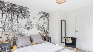 Ein Schlafzimmer mit einem Bett, einem Nachttisch, einer Lampe, einem Spiegel und einem Sessel.