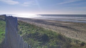 Ein Strand mit Holzzaun und einer Rasenfläche im Vordergrund.
