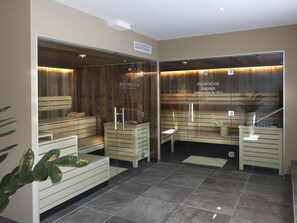 Experience the rejuvenating atmosphere of our sauna facilities, featuring two distinct areas: Kräutersauna and Finnische Sauna, each with wooden benches and a towel station.