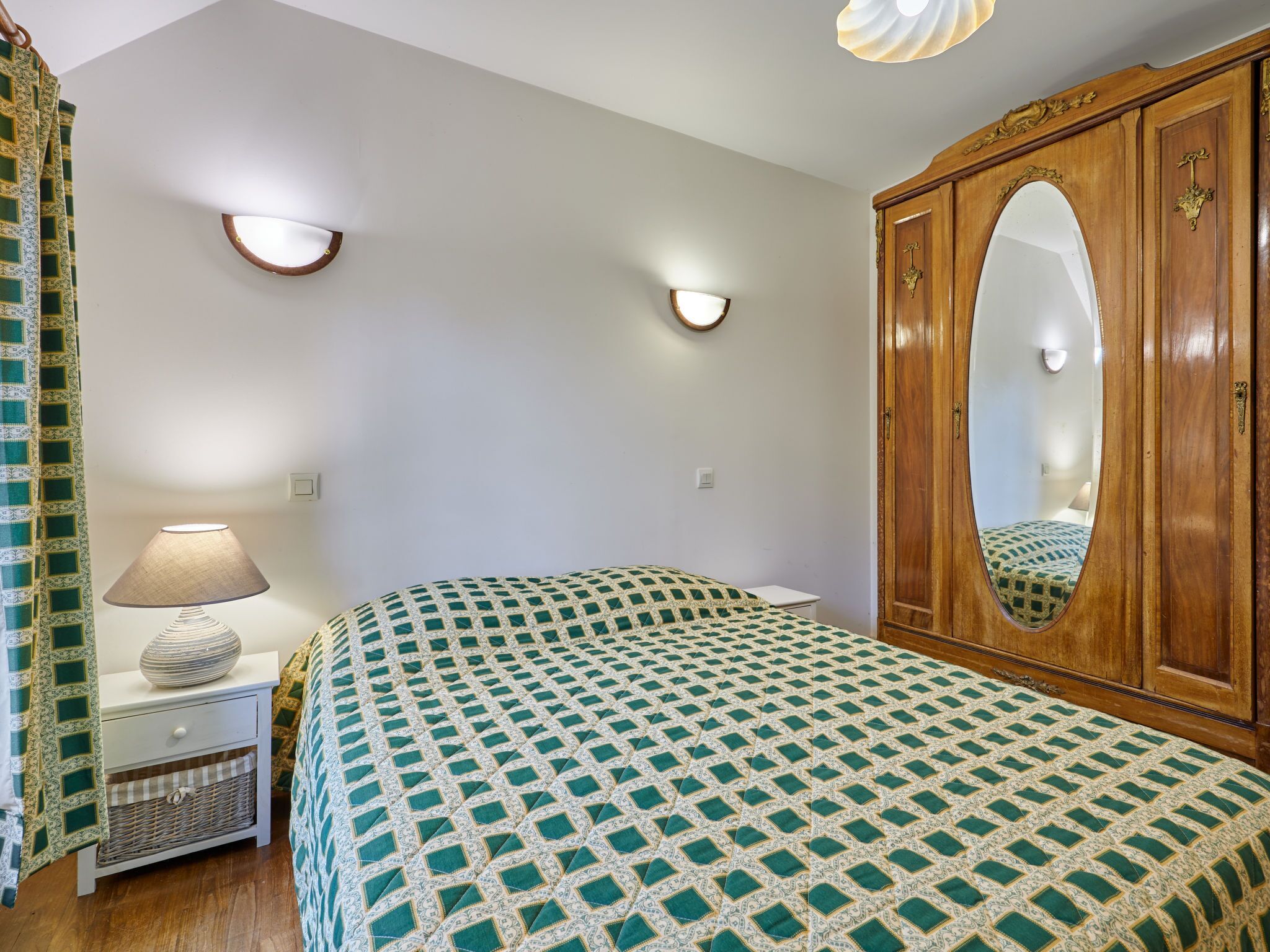 Un dormitorio con cama, mesita de noche, lámpara, armario y apliques de pared.