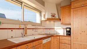 Eine moderne Küche mit Holzausstattung, einem großen Fenster und einer Kaffeemaschine.
