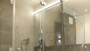 Une salle de bain moderne avec une douche à parois de verre, un meuble-lavabo en bois et un grand miroir.