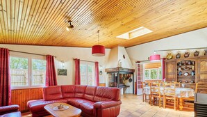 Un soggiorno accogliente con un divano in pelle rossa, un tavolino in legno e un'area pranzo con sedie e tavolo in legno.