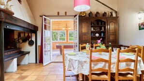 Zona pranzo con tavolo in legno, sedie e vista sull'esterno attraverso un'apertura.