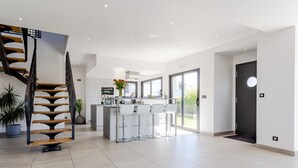Una cocina moderna con una isla central, una escalera y un comedor con taburetes de bar.