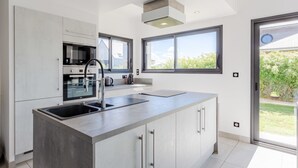 Una cocina moderna con una isla grande, electrodomésticos de acero inoxidable y vistas al exterior.