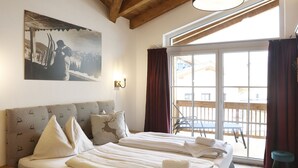 Quarto de hotel com uma cama grande, um quadro na parede e vista para a varanda externa.