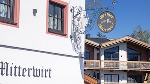 Um edifício com uma placa que diz 'Gasthof Gitterwart' e uma varanda com grades de madeira.
