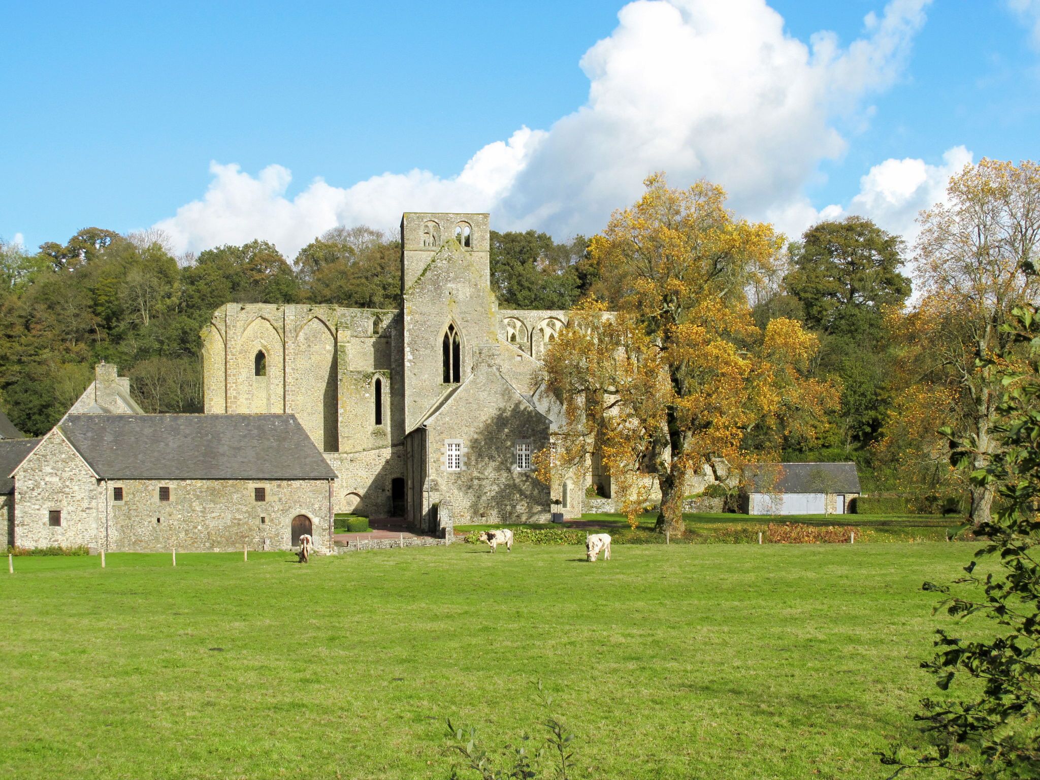 A historic stone building with a tower, surrounded by a grassy field and trees.