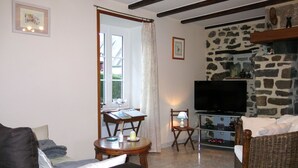 Un salon comprenant un canapé, une table à manger, un téléviseur et une cheminée en pierre.