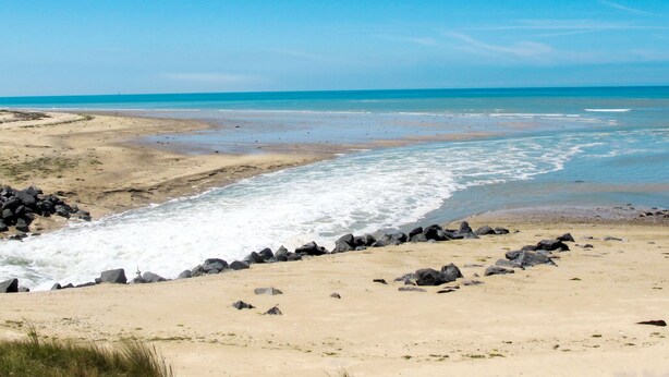 A beach with a rocky shoreline and waves crashing onto the sand.