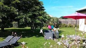 A garden with a lawn, a large tree, and outdoor furniture.