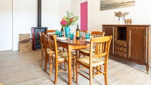 Un coin repas avec une table et des chaises en bois, un vase rempli de fleurs et un tableau accroché au mur.