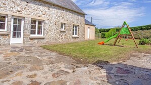 A stone building with a grassy yard and a children's play structure. - Le Plongeon by Interhome (Portbail)