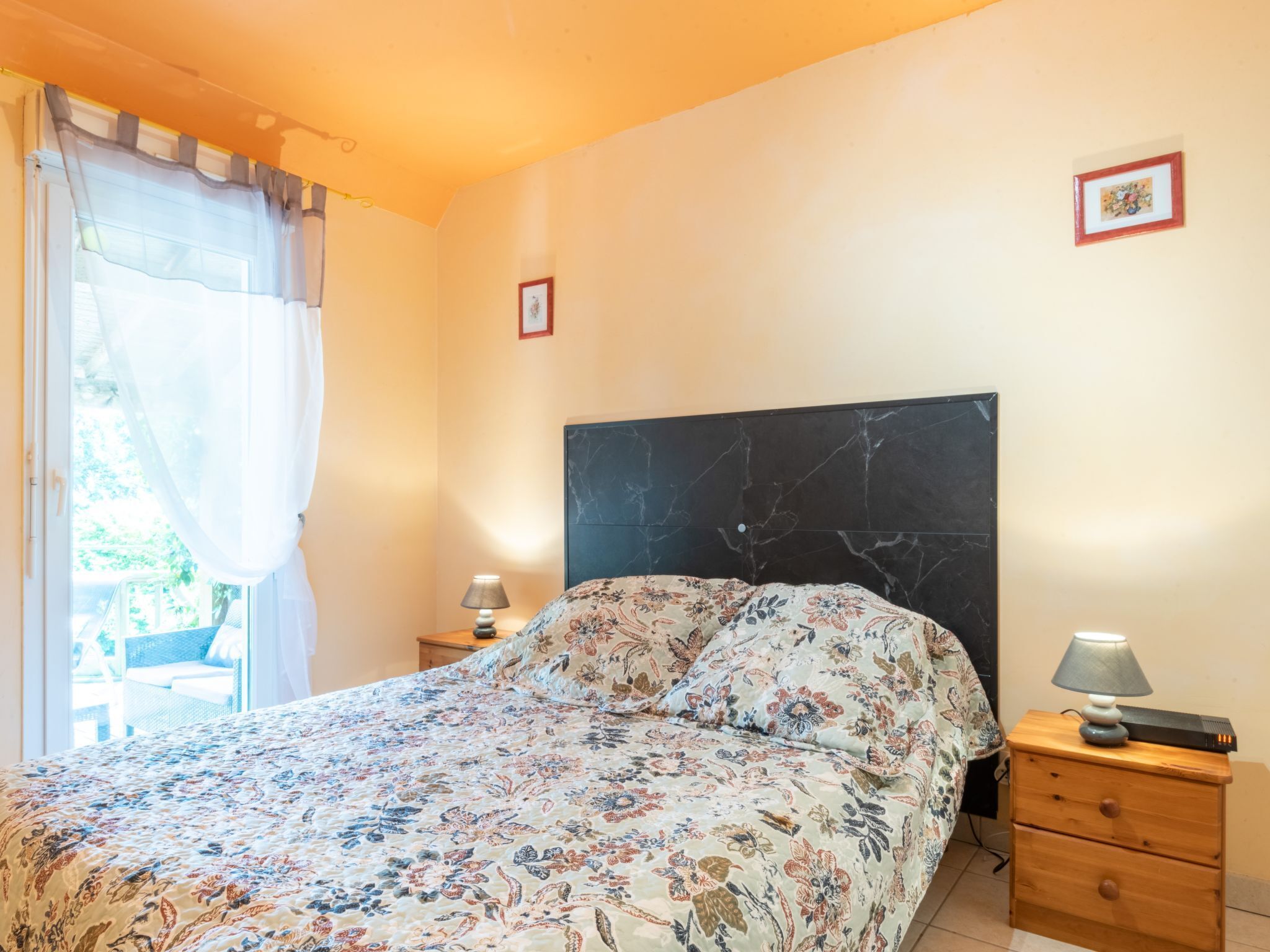 A bedroom with a bed, a nightstand, a lamp, and a framed picture on the wall.