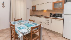 A compact kitchen with white cabinets, a gas stove, a microwave, and a coffee maker. - Alessandra by Interhome (Santa Teresa di Gallura)