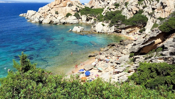 A rocky coastline with clear blue waters and a beach area with umbrellas and people. - Alessandra by Interhome (Santa Teresa di Gallura)