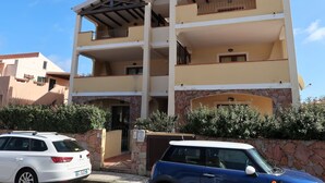 A multi-story building with a stone facade, balconies, and a gated entrance. - Alessandra by Interhome (Santa Teresa di Gallura)