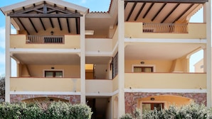 A multi-story building with balconies, a stone facade, and a flat roof. - Alessandra by Interhome (Santa Teresa di Gallura)