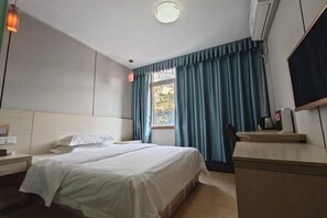 Une chambre d’hôtel avec un lit, une table de chevet et une fenêtre avec des rideaux.