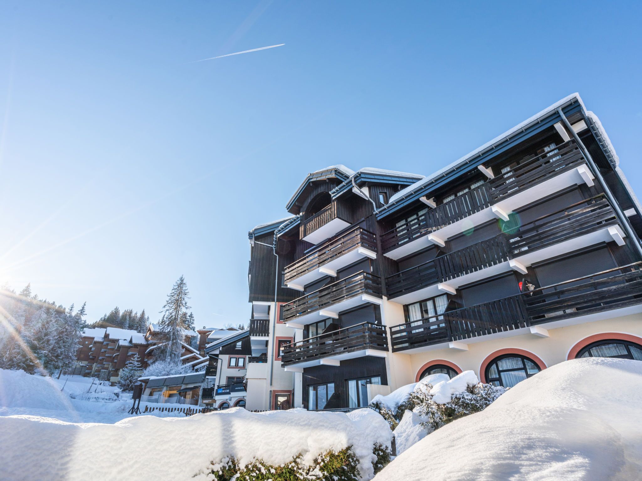 A multi-story hotel with balconies, a ski slope in the background, and snow-covered surroundings.