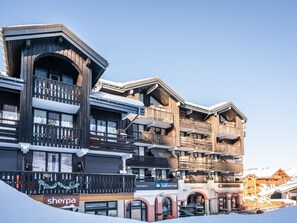 A multi-story hotel with balconies, ski rental signs, and a Sherpa store.