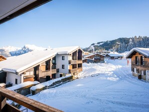 A snow-covered village with wooden buildings, a ski slope, and mountains in the background. - Grand Morillon by Interhome (Morillon)