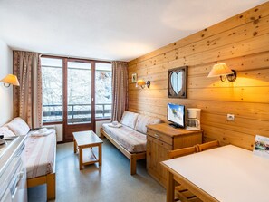 A cozy room with a bed, a desk, a chair, and a table. There is a window with curtains, a wall-mounted lamp, and a framed picture. - Grand Morillon by Interhome (Morillon)