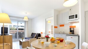 A modern hotel room with a dining area, kitchenette, and a balcony with a view. - Cap Med by Interhome (Le Grau du Roi)