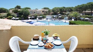 Una mesa de comedor con alimentos para el desayuno, una piscina y vistas a una zona turística.