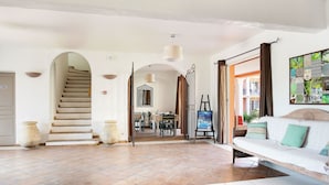 A spacious living area with a staircase, a dining area, and a sofa with cushions. - Résidence Odalys Référence La Palmeraie by Interhome (Grimaud)