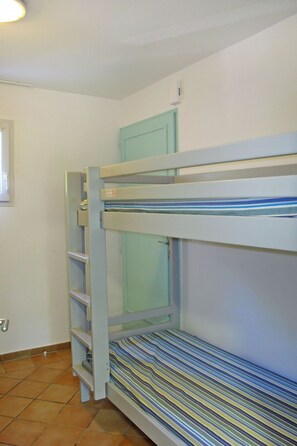 Un lit superposé avec un matelas à rayures, une étagère avec un coussin à rayures et une porte bleu clair.