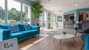 A modern hotel lobby with a blue sofa, a white coffee table, and a reception desk.