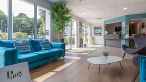 Un hall d’hôtel moderne avec un canapé bleu, une table basse blanche et un comptoir d’accueil.