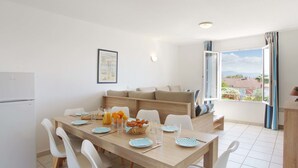 A modern kitchen with a dining table set for four, a refrigerator, and a view of the outdoors. - Odalys Référence Domaine des Eucalyptus by Interhome (Saint Aygulf)