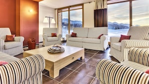 A modern living room with striped sofas and a wooden coffee table, large windows with a mountain view, and a floor lamp. - Résidence Odalys Collection Edenarc by Interhome (Les Arcs)
