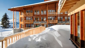 A multi-story wooden building with balconies, surrounded by snow. - Résidence Odalys Collection Edenarc by Interhome (Les Arcs)