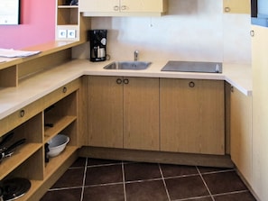A compact kitchen with wooden cabinets, a sink, and a coffee maker.