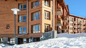 Un edificio in legno a più piani con ampie finestre e balconi, immerso nella neve.