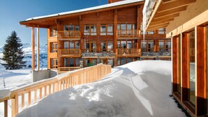 Un immeuble en bois à plusieurs étages, doté de balcons, et entouré de neige.