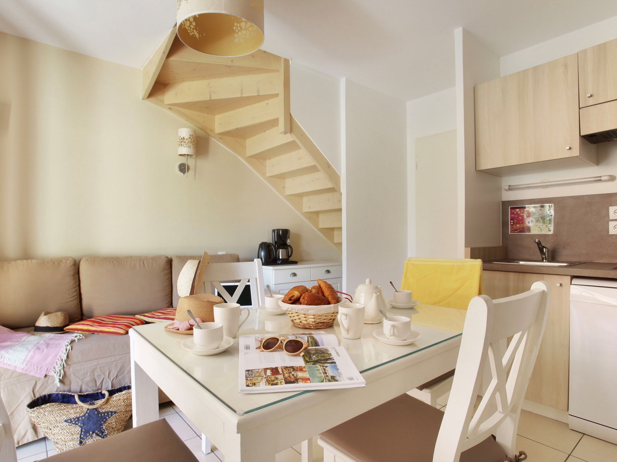 Un salon chaleureux avec une table à plateau en verre, un canapé et un escalier.