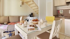 A cozy living area with a glass-top table, a sofa, and a staircase.